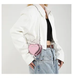 Detail of pink heart-shaped chain bag with shiny metallic finish and silver strap