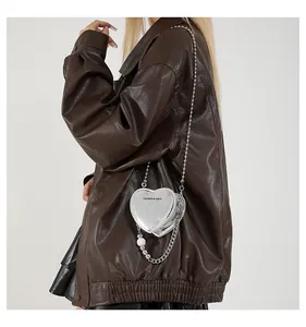 Detail of silver heart-shaped crossbody bag with mirror finish and pearl chain accessories