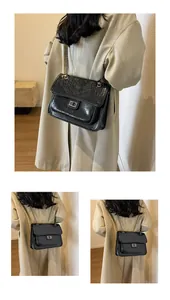 Détail du sac à chaîne noir avec surpiqûres en V et fermoir rotatif en métal argenté