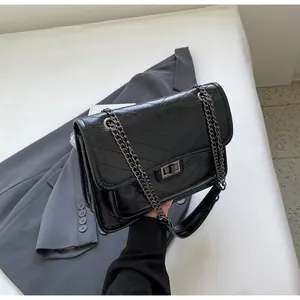 Détail du sac à chaîne vintage noir avec texture matelassée en V et fermoir métal