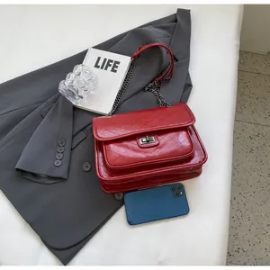 Détail du sac matelassé rouge avec chaîne, capacité montrée avec un smartphone et mode