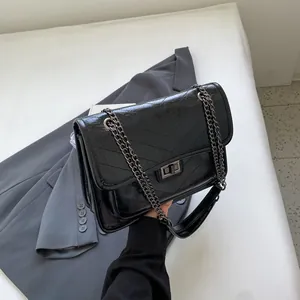 Sac à bandoulière noir tendance avec surpiqûres en V, fini brillant et boucle en métal