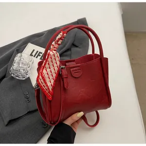 Détail du sac seau en similicuir rouge avec poignée en foulard et logo mode