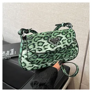Détail d'un sac imprimé léopard vert avec logo triangulaire en métal et texture douce