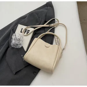 Sac seau trapèze beige avec poignée en foulard de soie sur un blazer gris