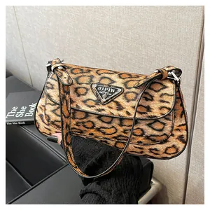 Gros plan du sac à bandoulière léopard avec logo triangle en métal et rabat chic