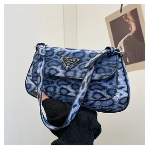 Détail du sac à bandoulière léopard bleu et noir avec plaque logo en métal triangulaire