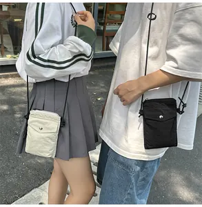 Detalle de bolsos de nylon para móvil en crema y negro con correas de cordón ajustables