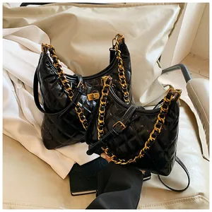 Detalle de bolso acolchado negro con cadena en tamaños grande y pequeño en un sofá