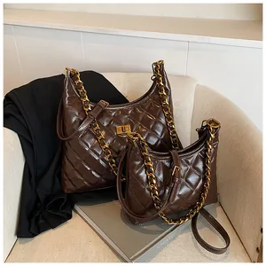 Detalle de bolso hobo de cuero acolchado marrón oscuro con cadena dorada y mini estuche