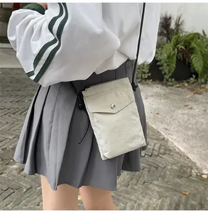 Detalle de mini bolso bandolera de nylon blanco roto con botón a presión plateado