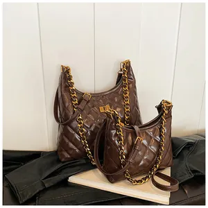 Primer plano de bolsos acolchados vintage marrón oscuro con cadena dorada sobre libros