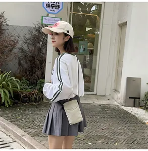 Detalle de mini bolso minimalista de nailon beige con cierre de botón y correa fina