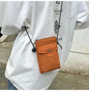 Primer plano del bolso naranja de nylon para móvil con bolsillos dobles y correa de cuerda