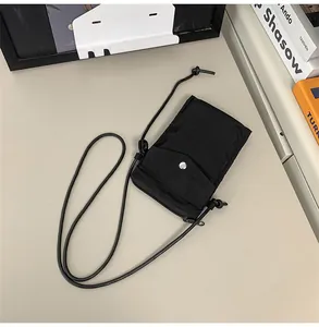 Detalle del mini bolso negro de nailon para móvil con botón de presión y cordón