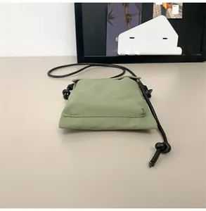 Vista detallada del bolso de nailon verde para móvil con correa de cuerda negra
