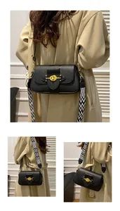 Détail du sac bandoulière en cuir noir avec boucle dorée et large bandoulière tissée
