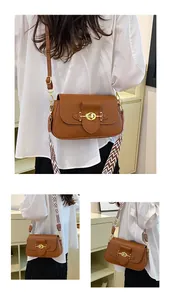 Détail du sac bandoulière en cuir marron avec fermoir doré et deux sangles interchangeables