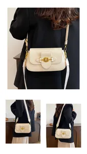 Détail du sac beige avec texture litchi et boucle de verrouillage rotative dorée