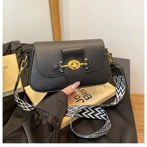 Détail du sac bandoulière en cuir noir grainé avec fermoir doré et sangle large