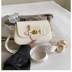 Détail d'un sac bandoulière crème avec fermoir rotatif doré et cuir texturé