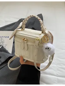 Chic cream leather handbag with silk scarf handle and plush charm, fashion crossbody style