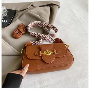 Détail du sac en cuir marron avec fermoir tournant doré et deux bandoulières