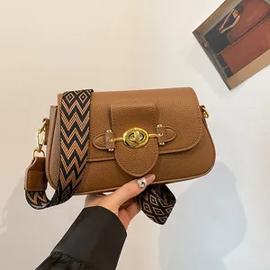 Sac bandoulière marron en cuir avec fermoir doré et large bandoulière tissée
