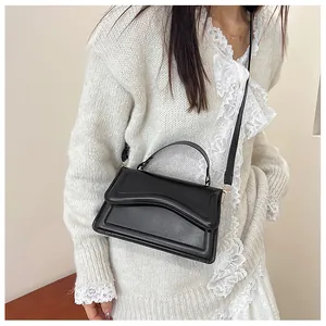 Detail view of black leather crossbody bag with unique wave stitching and gold hardware