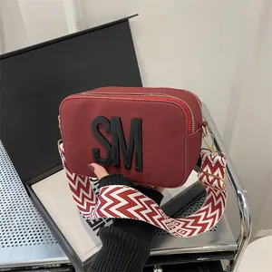 Deep red camera bag with wide wave strap and SM lettering for women crossbody style