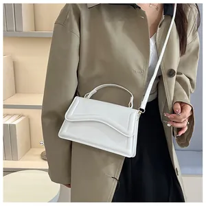 Detail of white PU leather crossbody bag featuring unique wavy edge flap and top handle