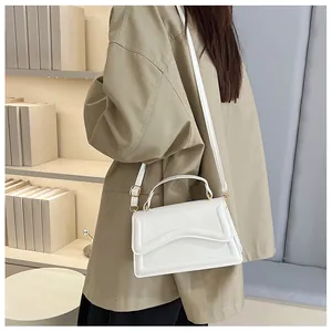 Lifestyle view of white PU leather crossbody bag with wave detail in a cozy bookstore