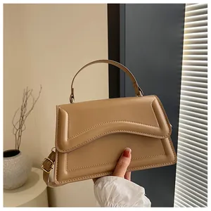 Detail of light brown faux leather handbag with geometric patterns and metal buckle