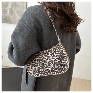 Dettaglio borsa baguette leopardata con zip dorata sulla spalla della modella