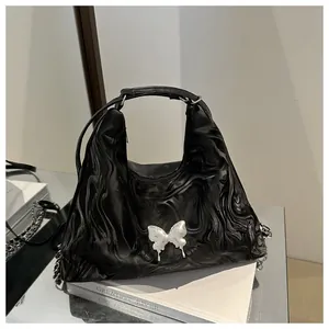 Detail of black water ripple handbag featuring a silver 3D butterfly with metal chain strap