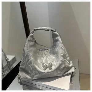 Close-up of silver liquid-metal textured tote bag featuring a 3D metal butterfly decoration
