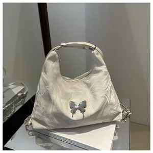 Detail of white marble print hobo bag with silver liquid metal butterfly decoration