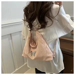 Detail of light pink shoulder bag with water ripple patterns and silver butterfly charm