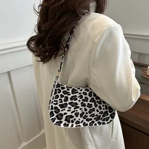 Borsa baguette alla moda con stampa leopardata e fibbia dorata vista di lato su una modella
