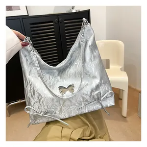 Dettaglio della borsa tote argento metallizzato con texture plissettata e fibbia a farfalla