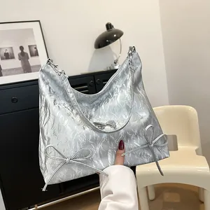 Borsa hobo argento metallizzato con fiocchi decorativi in un ambiente minimalista