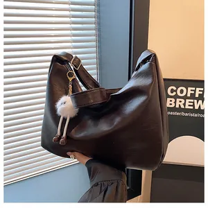 Detail of dark brown Hobo bag with wide strap and cute plush monster charm decoration