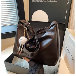 Detail of soft dark brown leather hobo bag with plush charm in elegant gift box setup