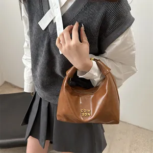 Braune Vintage Ölleder Knödeltasche mit Goldlogo als schicke Umhängetasche getragen