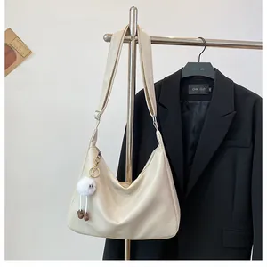 Detail of a beige PU leather hobo bag with zipper closure and cute plush ball pendant