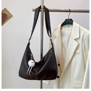 Detail of dark brown leather tote bag with a cute white plush monster keychain
