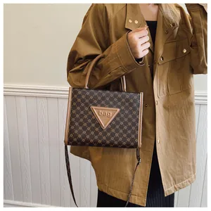 Detail of vintage tote bag with letter print and brown leather triangular patch