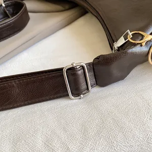 Detail shot of silver metal buckles and zipper on dark brown leather shoulder bag