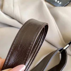Macro shot of dark brown leather strap with fine pebble grain and silver buckle detail
