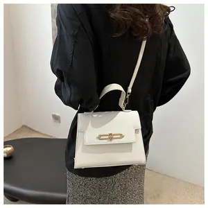 Détail du sac à bandoulière en cuir blanc avec boucle en métal doré et poignée supérieure